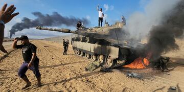 Palestinos celebran por un tanque israelí destruido en la valla de la Franja de Gaza al este del sur de Khan Younis (AP).