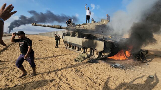 Palestinos celebran por un tanque israelí destruido en la valla de la Franja de Gaza al este del sur de Khan Younis (AP).