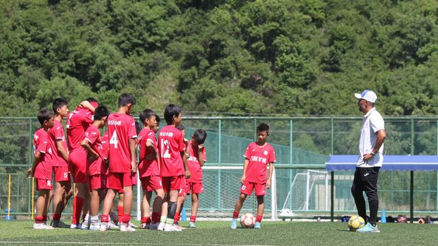 Nahuel Oyola hablando con sus pequeños dirigidos en el entrenamiento en su escuela de fútbol en China