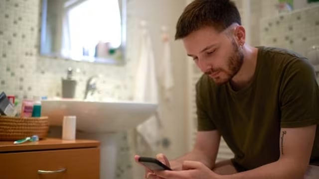 Hombre en el baño con el celular.