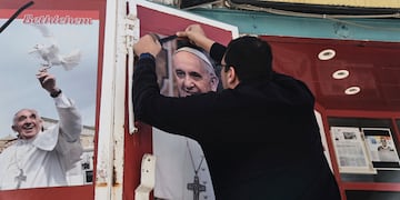 Un propietario de una tienda coloca un lazo negro sobre una foto del fallecido papa Francisco al conocer la noticia de su muerte a los 88 años, en Belén, Cisjordania, el lunes 21 de abril de 2025. (AP Foto/Mahmoud Illean)