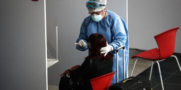 Una persona del personal sanitario realiza una prueba de coronavirus a una viajera en una terminal de transporte. (Foto: EFE/ Juan Ignacio Roncoroni)