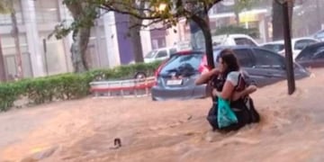 La imagen de una mujer tratando de caminar mientras el agua le llega casi a su cintura.
