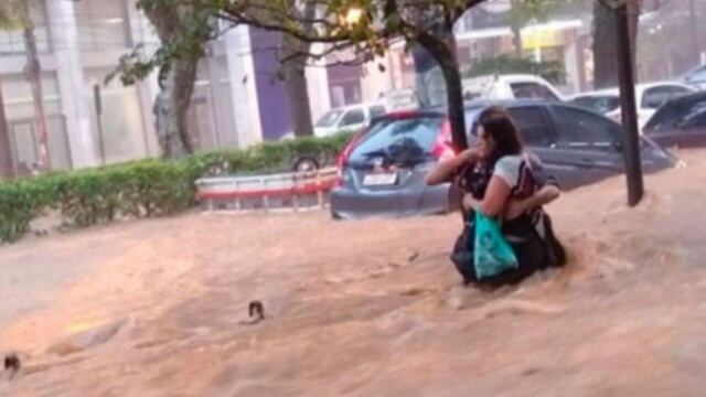 La imagen de una mujer tratando de caminar mientras el agua le llega casi a su cintura.