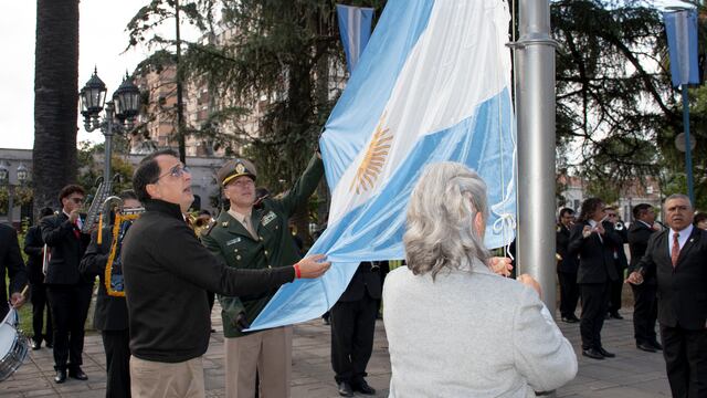 El concejal Lisandro Aguiar, el principal Gonzalo Rosalé y la contadora Virginia Llapur izaron la Bandera Nacional en uno de los mástiles ubicados al pie del monumento al General Belgrano.