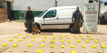 El utilitario de color blanco de fondo, para la imagen en primer plano del cargamento de cocaína que fue interceptado por la Gendarmería en el interior de la provincia de Jujuy.