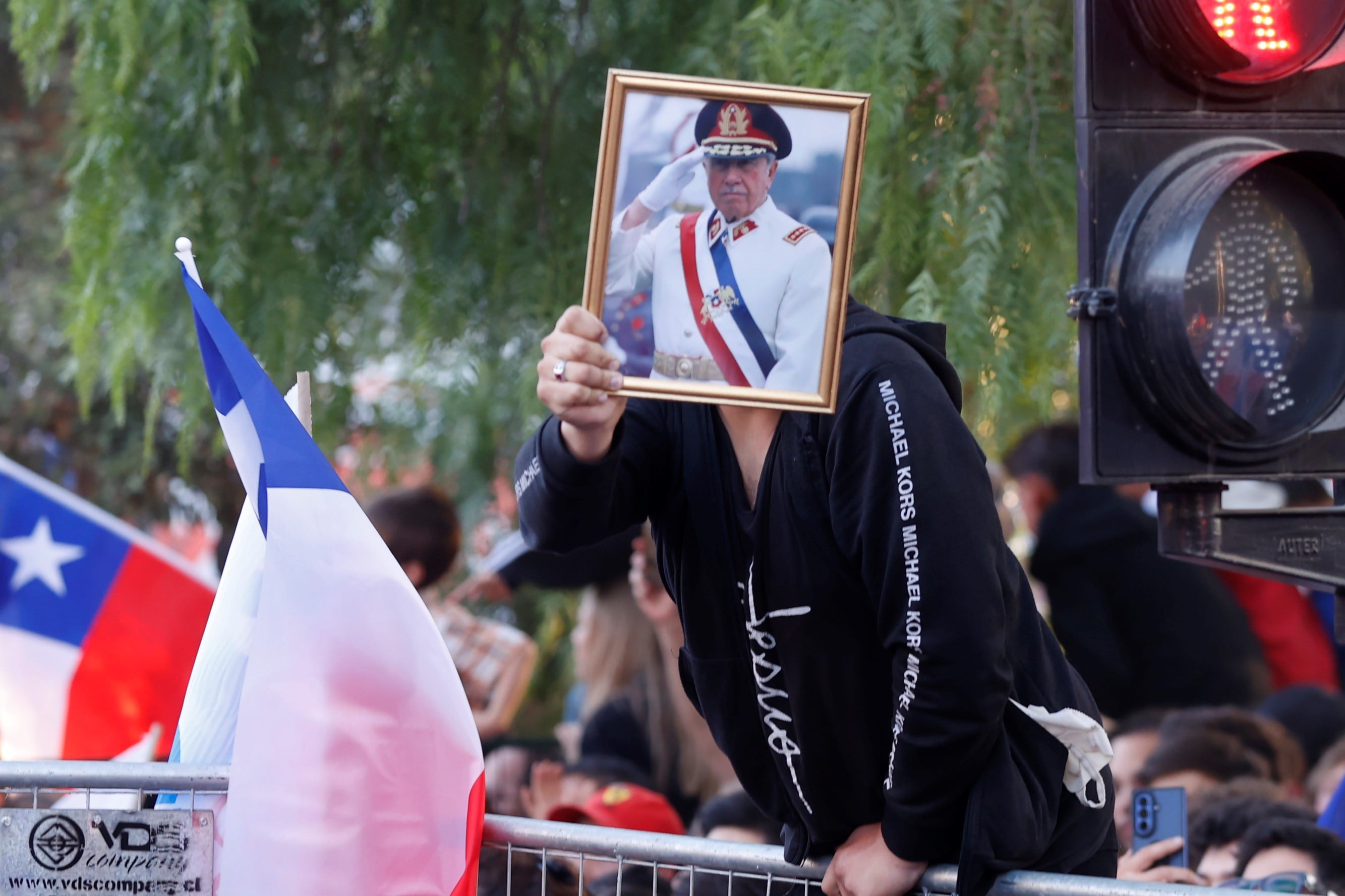 Un simpatizante del candidato a la Presidencia de Chile por el Partido Republicano y el Partido Social Cristiano, José Antonio Kast, sostiene en una calle de Santiago una fotografía de Augusto Pinochet, mientras se conoce los primeros resultados de la segunda vuelta presidencial.