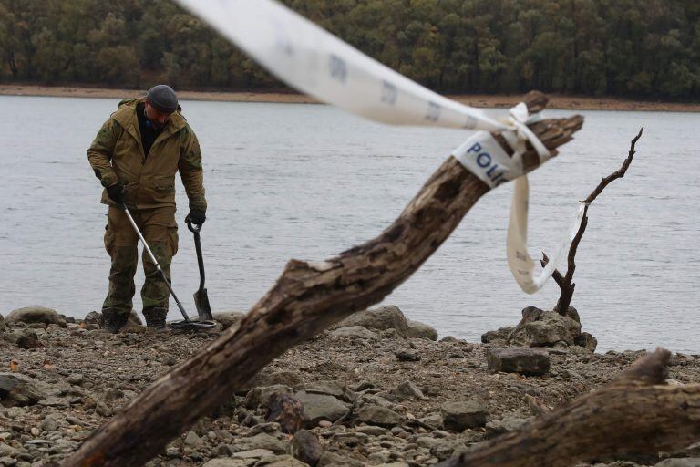 Arqueólogos húngaros inspeccionan el sitio donde encontraron monedas de los siglos XVI al XVII y armas especiales en las orillas del río Danubio. Crédito: Photo by FERENC ISZA / AFP.