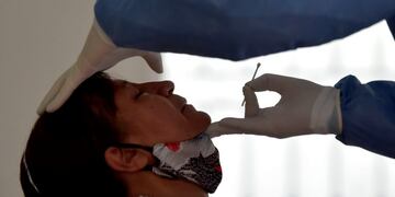 A health worker takes a sample for a COVID-19 test from a resident of the Kennedy neighborhood, one of the areas with the highest rate of positive cases in Bogota, on June 11, 2020\u002E (Photo by Raul ARBOLEDA / AFP) hisopado