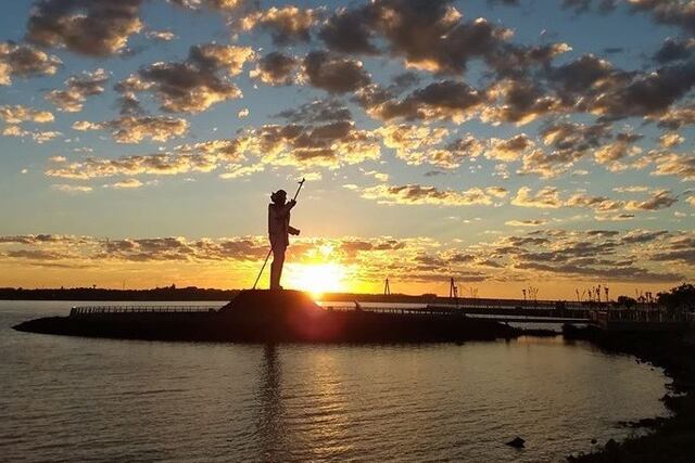 Amanece en Posadas y el sol se levanta del este por dertrás de la estatua a Andresito\u002E