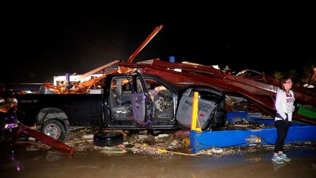 Ernestine Cook of Canton inspects the damage done to the I-20 Dodge dealership after a tornado hit Canton, Texas, Saturday, April 29, 2017. Cars and trucks were piled high and the service area was destroyed. Authorities say fatalities have been reported and dozens of people were taken to hospitals after a tornado hit the small city in East Texas. (Tom Fox/The Dallas Morning News via AP)