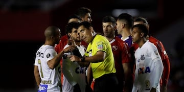 El árbitro peruano Diego Haro (c) discute con el uruguayo Carlos Sánchez, de Santos, quien no podía jugar ante Independiente por una sanción que arrastraba de su paso por River\u002E EFE/David Fernández