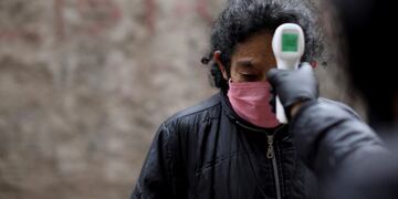 A volunteer measures the temperature of a resident inside the Fraga slum during a government-ordered lockdown to curb the spread of the new coronavirus, in Buenos Aires, Argentina, Saturday, June 6, 2020\u002E (AP Photo/Natacha Pisarenko)
