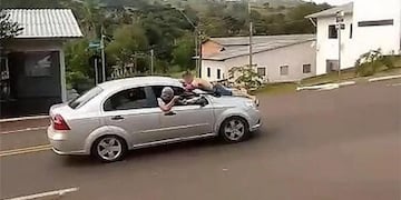 Delincuentes se llevan a uno de los rehenes sobre el capot del auto\u002E
