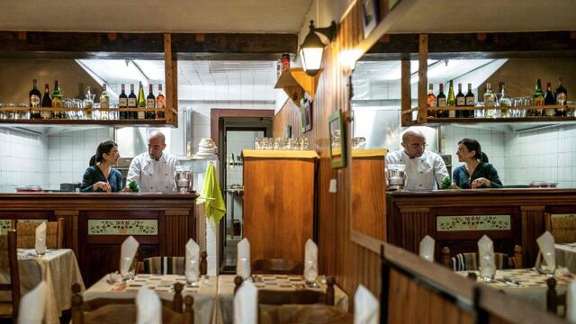 Cesar Asfar (2L) and his wife Rima, refugees from Syria and restaurant owners, are reflected in a mirror as they work in the kitchen of their restaurant