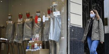 A woman walks past the window of a store displaying mannequins wearing face masks -since it is forbidden to sell clothing during the lockdown imposed by the government against the spread of the new coronavirus- in Buenos Aires, Argentina, on May 22, 2020\u002E - Argentina is expected to pass the 10,000 infections of COVID-19 since the first positive case on March 3\u002E (Photo by JUAN MABROMATA / AFP)  negocios comercios