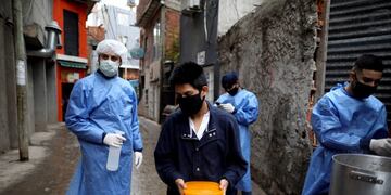 A resident leaves with a container of free food he received from a soup kitchen inside the Fraga slum during a government-ordered lockdown to curb the spread of the new coronavirus, in Buenos Aires, Argentina, Saturday, June 6, 2020\u002E (AP Photo/Natacha Pisarenko)