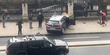 People stand near a crashed car and an injured person lying on the ground, right, on Bridge Street near the Houses of Parliament in London, Wednesday, March 22, 2017. Britain has been targeted Wednesday by what authorities are calling a terrorist incident