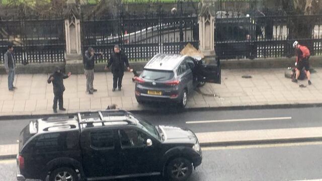 People stand near a crashed car and an injured person lying on the ground, right, on Bridge Street near the Houses of Parliament in London, Wednesday, March 22, 2017. Britain has been targeted Wednesday by what authorities are calling a terrorist incident