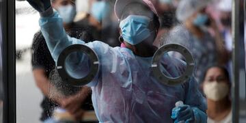 PA1001\u002E CIUDAD DE PANAMÁ (PANAMÁ), 24/8/2020\u002E Personal médico limpia una cabina donde se realizan pruebas de hisopado para detectar coronavirus hoy en una estación express en el distrito de San Miguelito en ciudad de Panamá (Panamá)\u002E Personas formadas en una larga fila esperaban este lunes ser atendidas en un centro de \