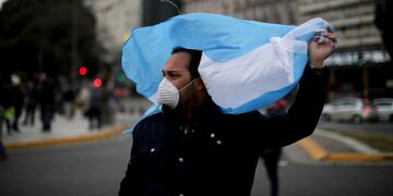 A man holding a national flag and wearing a protective face masks takes part in a protest demanding an end to the government-ordered lockdown put in place help curb the spread of the new coronavirus, in Buenos Aires, Argentina, Saturday, May 30, 2020\u002E (AP Photo/Natacha Pisarenko)