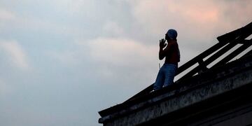 TOPSHOT - An inmate gestures as he sits on a destroyed roof of the Villa Devoto prison during a riot in demand of preventive measures against the spread of COVID-19 after a case of the novel coronavirus was confirmed inside the facility, in Buenos Aires on April 24, 2020\u002E (Photo by Ronaldo SCHEMIDT / AFP)