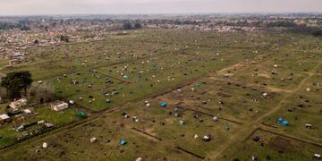 TOPSHOT - Aerial view showing tents and improvised shelters set up by homeless people in vacant land outside Guernica, in the province of Buenos Aires, south of the Argentine capital, on August 28, 2020 amid rising poverty in an economic crisis exacerbated by the COVID-19 novel coronavirus pandemic\u002E - Outdoors or under makeshift tents, about 2,500 people have been defying justice, and COVID-19, for more than a month, when they occupied empty lots in Buenos Aires Province, the most populous of the country and where the pandemic is hitting the hardest\u002E Scattered in over 100 hectares of vacant land, children run around and adults talk, while the police guards the area\u002E Prevention measures against the novel coronavirus barely exist here\u002E (Photo by Ronaldo SCHEMIDT / AFP)