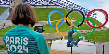 La voluntaria olímpica Manuella Mallam se toma una foto con los anillos olímpicos afuera del Bercy Arena. (AP)