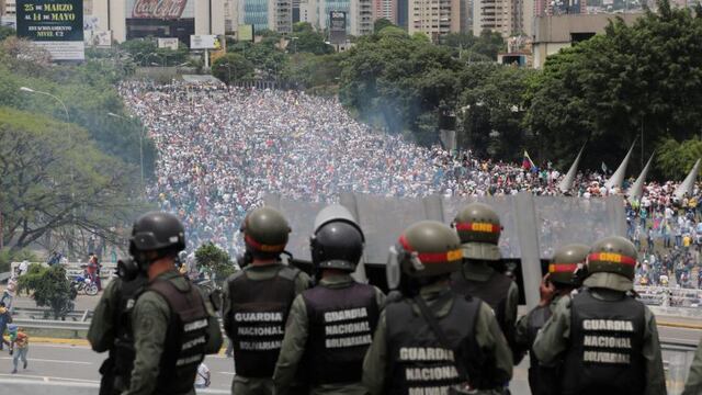 Bolivarian National Guards stand on a highway overlooking an anti-government march trying to make its way to the National Assembly in Caracas, Venezuela, on Wednesday, May 3, 2017. Driving the latest outrage is a decree by President Nicolas Maduro to begin the process of rewriting Venezuela's constitution, which was pushed through in 1999 by his predecessor and mentor, the late President Hugo Chavez. (AP Photo/Fernando Llano)