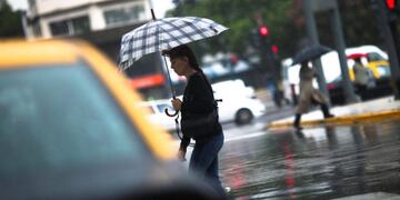 BAS102. BUENOS AIRES (ARGENTINA) 13/02/2017.- Personas se protegen de la lluvia hoy, lunes 13 de febrero de 2017, en Buenos Aires (Argentina). El viento y la lluvia azotaron hoy Argentina, que comienza la recta final de un verano cuya previsiu00f3n meteorolu00f3g