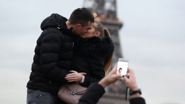 A couple of tourists kiss as they pose with the Eiffel Tower in background at the Trocadero esplanade, in Paris on December 31, 2019\u002E (Photo by Zakaria ABDELKAFI / AFP) paris francia turismo en la torre eiffel pareja beso besandose turistas esplanada trocadero