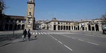 Una mujer pasea su perro en las calles vacías de Bérgamo, una de las ciudades más afectadas por el brote de coronavirus, en el norte de Italia. (AP/Luca Bruno)