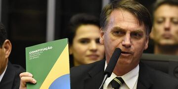 (FILES) In this file photo taken on November 06, 2018 Brazilian far-right president-elect, Jair Bolsonaro (R), holds a constitution beside his vice president Hamilton Mourao during the ceremony celebrating the 30th anniversary of the Brazilian constitution in the National Congress in Brasilia\u002E - Brazil's next president, Jair Bolsonaro, takes office on January 1, 2019 with promises to radically change the path taken by Latin America's biggest country by trashing decades of center-left policies\u002E But while the far-right politician enjoys sky-high popularity of 75 percent going into the top job, the challenges to his agenda are formidable\u002E (Photo by EVARISTO SA / EVARISTO SA / AFP)