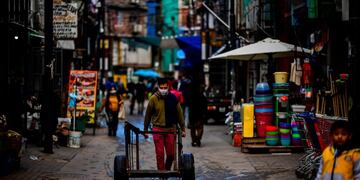 A man wearing a face mask as a preventive measure against the novel coronavirus, COVID-19, pushes a cart in Villa 31 shantytown in downtown Buenos Aires, on May 5, 2020\u002E - Villa 31, the oldest shantytown in Buenos Aires, is separated only by an avenue from exclusive neighbourhoods of the capital\u002E Crowded, hungry and suffering water services faults, residents of the slum now face the menace of COVID-19\u002E (Photo by Ronaldo SCHEMIDT / AFP)