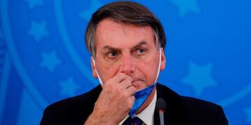 (FILES) In this file photo taken on March 20, 2020 Brazil's President Jair Bolsonaro gestures during a press conference on the coronavirus pandemic COVID-19 at the Planalto Palace in Brasilia\u002E - Two tweets by Brazilian president Jair Bolsonaro in which he questioned quarantine measures aimed at containing the novel coronavirus were removed on March 29, 2020, on the grounds that they violated the social network's rules\u002E The far-right leader had posted several videos in which he flouted his government's social distancing guidelines by mixing with supporters on the streets of Brasilia and urging them to keep the economy going\u002E (Photo by Sergio LIMA / AFP)
