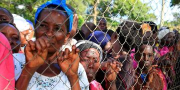People gather at the perimeter fence to watch as rescue and recovery missions search for the bodies of dead passengers after a cruise boat capsized in Lake Victoria off Mukono district, Uganda November 25, 2018\u002E REUTERS/James Akena