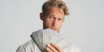 hombre con muchos dólares en la mano. Imagen ilustrativa.