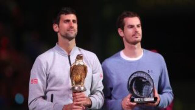 Serbia's Novak Djokovic (L) poses with the winner's trophy after beating Britain's Andy Murray during their final tennis match at the ATP Qatar Open in Doha on January 7, 2017. / AFP PHOTO / KARIM JAAFAR