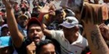 Handout picture released by courtesy of Panorama showing people protesting for lack of cash and new notes outside Venezuela's Central Bank (BCV) in Maracaibo city, Zulia State, on December 16, 2016.nVenezuelans lined up to deposit 100-unit banknotes befor