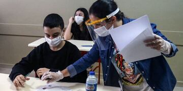 Turkish 8th grade students sits before starting their High School Transition System (LGS) examination at the Fevzi Ozbey secondary school in Ankara on June 20, 2020\u002E (Photo by Adem ALTAN / AFP)  clases distanciamiento social nueva normalidad estudiantes secundaria  aula de secundaria   meastro  maestra con  mascara  barbijo barbijos