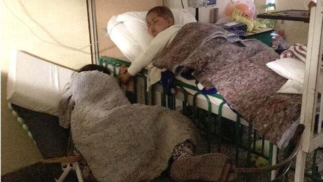 Thiago y su mamá, en la sala de oncología del Hospital de Niños dormidos y tomaditos de la mano\u002E (Facebook Juan Pablo Rodríguez)