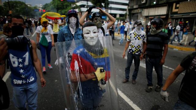 An anti-government protester wearing a mask carries a shield during clashes with security forces in Caracas, Venezuela, Wednesday, April 19, 2017. Tens of thousands of opponents of President Nicolas Maduro flooded the streets of Caracas in what's been dub