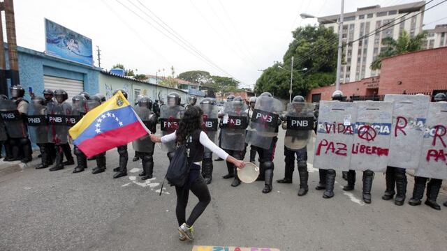 Una manifestante sostiene una bandera de Venezuela y baila frente a la policu00eda durante una protesta opositora el 01/06/2017 en Valencia, Venezuela. foto: Juan Carlos Hernandez/ZUMA Wire/dpa