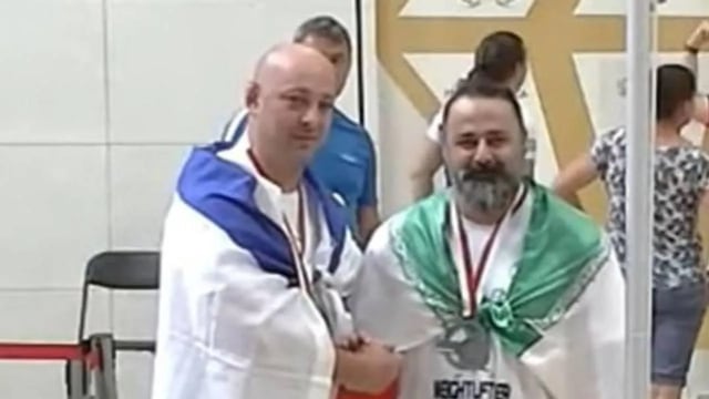Maksim Svirsky y Mustafa Rajaei, atletas israelí e iraní respectivamente, dándose la mano luego de quedar tercero y segundo en una competencia de levantamiento de pesas en Polonia. Foto: Los Andes.
