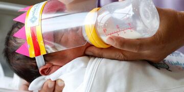 -FOTODELDÍA-RUN1096\u002E SAMUT PRAKAN, 08/04/2020\u002E- Un bebé recién nacido tailandés usa un protector facial para evitar el contacto con la enfermedad COVID-19 y el coronavirus mientras es alimentado con biberón por una enfermera, en el Hospital Princ Suvarnabhumi, en la provincia de Samut Prakan, Tailandia, 08 de abril de 2020\u002E El hospital proporciona protectores faciales recién nacidos para prevenir la propagación continua de la enfermedad COVID-19 causada por el coronavirus SARS-CoV-2\u002E EFE/EPA/RUNGROJ YONGRIT