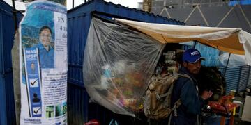 A man holds a bike next to an election poster of presidential candidate Luis Arce of Movement to Socialism party (MAS) in El Alto, on the outskirts of La Paz, Bolivia October 17, 2020\u002E REUTERS/David Mercado