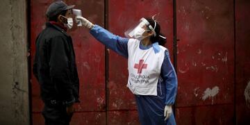 Voluntarios de la Cruz Roja toman la temperatura a un hombre (AP Photo/Natacha Pisarenko)
