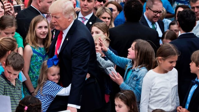 US President Donald Trump receives a hug during the Easter Egg Roll on the South Lawn of the White House April 17, 2017 in Washington, DC. / AFP PHOTO / Brendan Smialowski