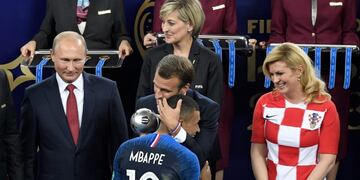 French President Emmanuel Macron (rear C) congratulates France's forward Kylian Mbappe (front C) as he receives the trophy for best young player next to Russian President Vladimir Putin (L) and Croatian President Kolinda Grabar-Kitarovic (R) during the trophy ceremony at the end of the Russia 2018 World Cup final football match between France and Croatia at the Luzhniki Stadium in Moscow on July 15, 2018\u002E / AFP PHOTO / GABRIEL BOUYS / RESTRICTED TO EDITORIAL USE - NO MOBILE PUSH ALERTS/DOWNLOADS