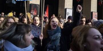 A woman holds a placard reading